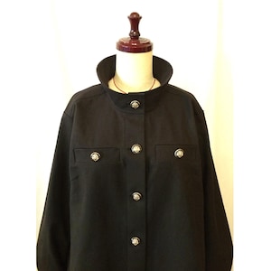 May include: A black jacket with a mandarin collar and decorative, ornate gold buttons. The jacket has two chest pockets and long sleeves. The garment is displayed on a mannequin.