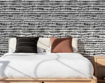 May include: A white bed with a black and white patterned headboard. The bed has a white duvet and two pillows, one brown and one black. The bed is sitting on a wooden frame.