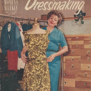 Puede incluir: Una mujer con un vestido azul se encuentra junto a un maniquí que lleva un vestido estampado en amarillo y marrón. El maniquí está sobre un soporte y la mujer está sujetando el vestido. La imagen es de un suplemento de revista vintage titulado "Confección" por Lucille Rivers.