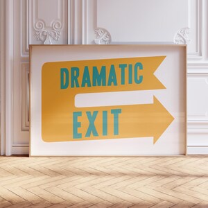 May include: A white framed poster with a yellow arrow pointing to the right. The arrow has the words "Dramatic Exit" written in teal blue letters.