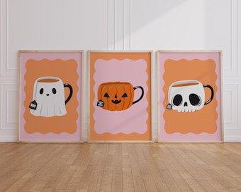 May include: Three framed art prints featuring Halloween-themed teacups. One is a ghost, one a jack-o'-lantern, and the last a skull. Each teacup has a black handle and a tea bag. The backgrounds are orange and pink.