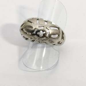 May include: A silver ring with a delicate, intricate design. The ring is made of a thin band with a wide, openwork design that resembles a flower or a star.