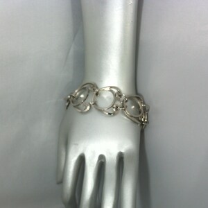 May include: A silver bracelet with a chain link design featuring interlocking circles.