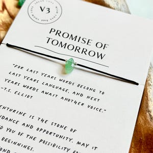 Könnte beinhalten: Schwarzes Armband mit einem hellgrünen Aventurin-Edelstein. Die Karte zeigt "Promise of Tomorrow" mit einem Zitat von T.S. Eliot und Informationen über Aventurin.
