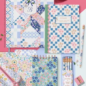 May include: A selection of stationery items with floral and geometric patterns in pastel shades. Includes notebooks, pencils, a pencil case, and decorative tape. The items feature a blue, pink, and white colour scheme with the text "Muse Bloom designs" and "Writing Pencils."