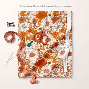 May include: A close-up of a fabric with a floral pattern in shades of orange, white, and brown. The fabric is laid out on a white surface with a measuring tape, scissors, and two sewing needles.
