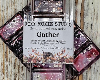 May include: Two rectangular wax melt bars in clear plastic packaging. The dark purple wax is infused with iridescent glitter. The label reads FOXY MOXIE STUDIO, Hand poured wax melts, Gather, Scent Notes: Cinnamon, Apple, Peach, Wild Berries, and Clove, 1.75 oz / 50g.