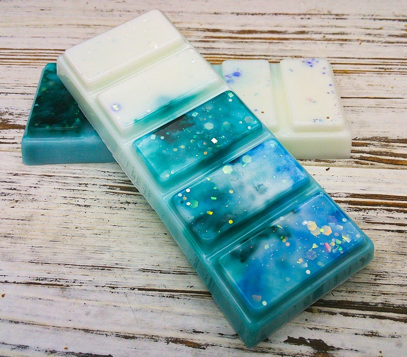 K&ouml;nnte beinhalten: Ein blauer und wei&szlig;er Wachsschmelzer mit glitzerndem Finish. Der Wachsschmelzer ist in sechs Quadrate unterteilt.