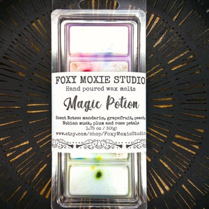 May include: A clear plastic package containing wax melts. The label reads "FOXY MOXIE STUDIO Magic Potion" with scent notes listed. The wax melts are rectangular and multi-colored. The package contains 1.75 oz of wax melts.