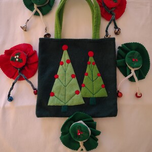 May include: A green felt tote bag with two green felt Christmas trees and red felt ornaments. The bag has green felt handles and comes with five small felt ornaments with bells.
