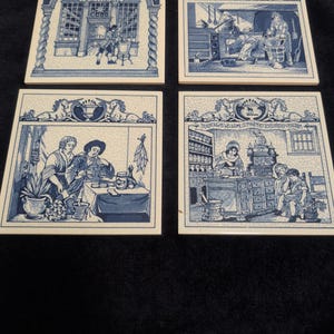 May include: Four square ceramic tiles with blue and white illustrations. Each tile depicts a different scene, including people in a shop and a kitchen. The tiles have a decorative border and are arranged in a 2x2 grid.