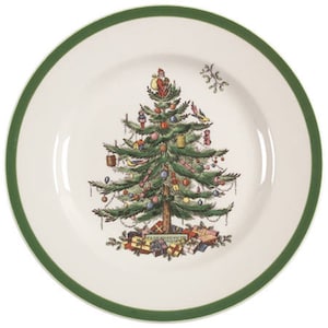 May include: A white ceramic Christmas plate with a green rim features a colorful illustration of a Christmas tree decorated with ornaments, presents, and a Santa Claus figure. The text "To All A Merry Christmas" is printed at the base of the tree.