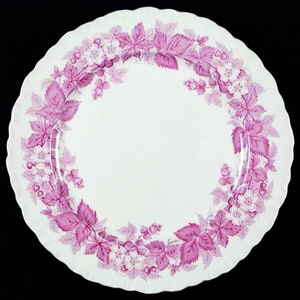 May include: A white dinner plate with a pink and white floral pattern around the edge. The flowers are pink with white centers and are surrounded by pink leaves.