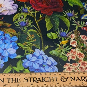 May include: A fabric with a dark background, featuring a vibrant floral pattern. The design includes roses, tulips, and other flowers in shades of red, blue, white, and yellow. A wooden ruler with the text "ON THE STRAIGHT & NARROW" is at the bottom.