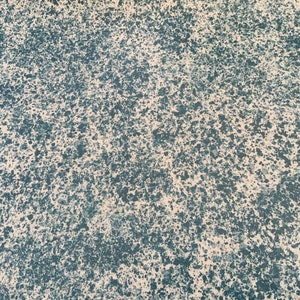 Könnte beinhalten: Nahaufnahme einer strukturierten Oberfläche mit einem gesprenkelten Muster aus blauer und weißer Farbe. Die Oberfläche hat eine raue, unebene Textur.