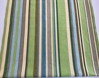 May include: A rectangular textile with vertical stripes in shades of green, blue, beige, and black. The stripes vary in width, creating a visually dynamic pattern. The fabric appears to be woven.