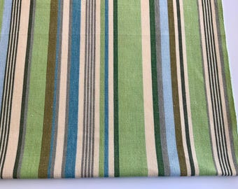 Op de afbeelding: Close-up van een stof met verticale strepen in tinten groen, blauw, beige en bruin. De strepen variëren in breedte en creëren een textuurpatroon. De stof lijkt linnen of een vergelijkbaar geweven materiaal te zijn.