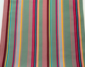 Op de afbeelding: Gestroomde stof met afwisselende banden in groen, roze, geel, rood en blauw.