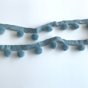 May include: A length of light blue trim with pom-poms. The trim is made of a soft, fuzzy material and is perfect for adding a touch of whimsy to any project.
