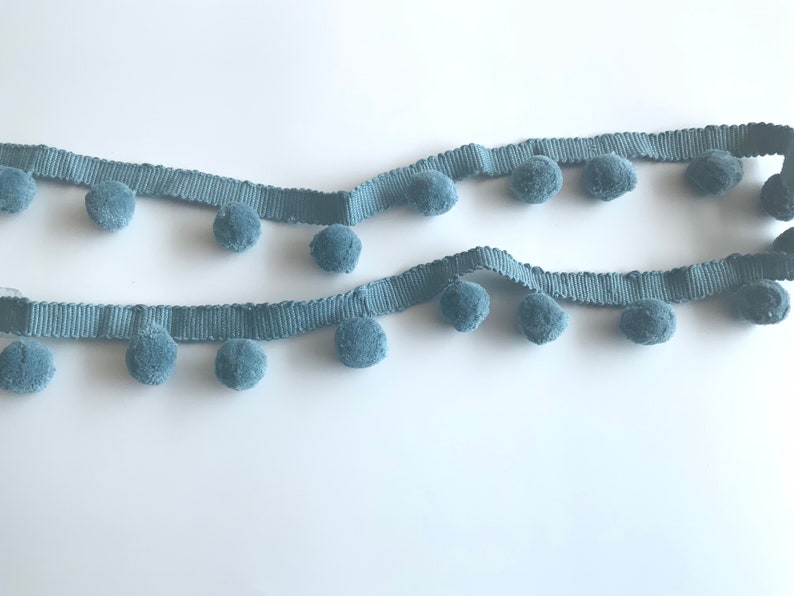 May include: A length of light blue trim with pom-poms. The trim is made of a soft, fuzzy material and is perfect for adding a touch of whimsy to any project.