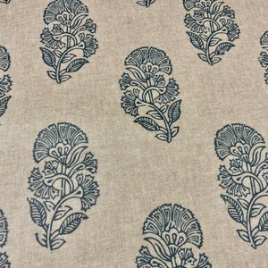 May include: A beige fabric with a repeating pattern of dark blue floral designs. The floral designs are intricate and detailed, resembling paisley patterns.