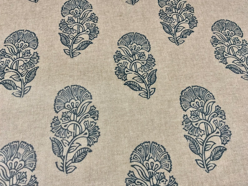 May include: A beige fabric with a repeating pattern of dark blue floral designs. The floral designs are intricate and detailed, resembling paisley patterns.