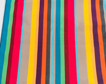 Op de afbeelding: Een kleurrijke gestreepte stof met afwisselende banden in beige, geel, oranje, paars, rood, teal, groen en donkerrood.