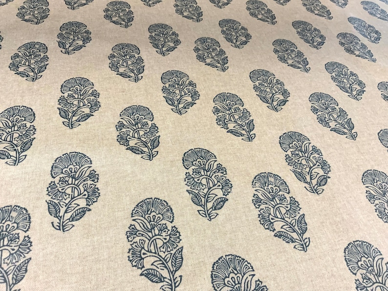 May include: A beige fabric with a repeating pattern of dark blue floral designs. The fabric has a subtle texture.