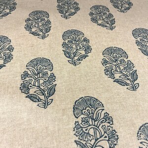 May include: A beige fabric with a repeating pattern of dark blue floral designs. The floral designs are intricate and detailed, resembling paisley.