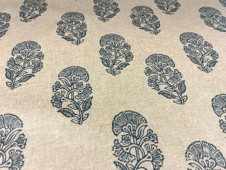 May include: A beige fabric with a repeating pattern of dark blue floral designs. The floral designs are intricate and detailed, resembling paisley.