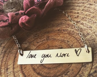 May include: A gold necklace with a bar pendant that says "love you more" in handwritten script with a small heart symbol.