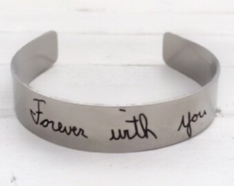 May include: A silver bangle bracelet with the words "Forever with you" engraved on it.