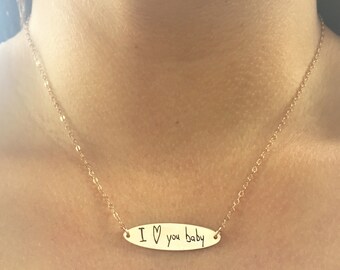 May include: A gold chain necklace with a small oval pendant that says "I love you baby" in handwritten script.