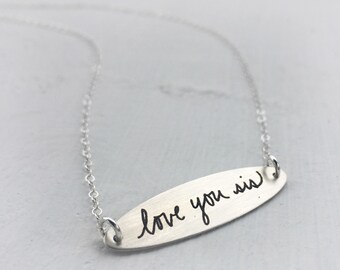 May include: Silver necklace with a long oval pendant that says "love you sis" in handwritten script.