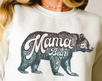 May include: White sweatshirt with a black and gray bear graphic and the text "Mama Bear" in a vintage style font.