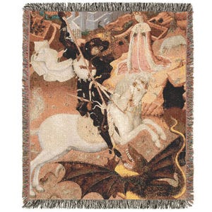 May include: Woven throw blanket featuring a medieval painting of a knight on horseback slaying a dragon. The artwork depicts a knight in black armor, a white horse, and a dragon with brown wings. The blanket has a fringed edge and a beige background.