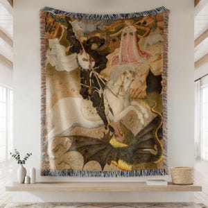May include: Woven tapestry throw blanket featuring a medieval painting of a knight on horseback slaying a dragon. The artwork depicts a knight in black armor, a white horse, and a green dragon. The blanket has a fringed edge.