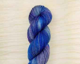 Puede incluir: Un ovillo de hilo azul, morado y gris con un patrón de color variado.