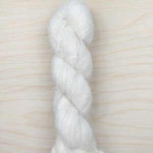 May include: A skein of white yarn with a fuzzy texture.