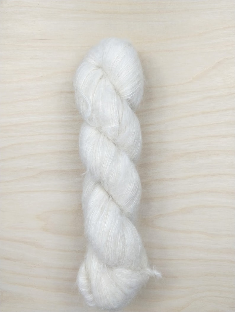 May include: A skein of white yarn with a fuzzy texture.