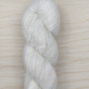 May include: A skein of white yarn with a soft, fluffy texture.