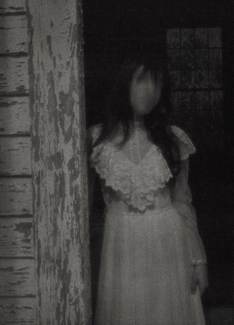 May include: A long-sleeved white dress featuring a high neckline with a prominent lace-trimmed ruffled collar and a fitted bodice. The garment is captured in a grainy, monochromatic aesthetic, highlighting the intricate lace textures and the flowing skirt.