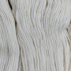May include: A close-up of a skein of white yarn. The yarn is soft and fluffy, and it is perfect for knitting or crocheting.