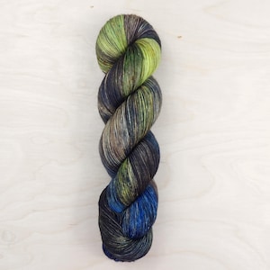 May include: A skein of yarn in shades of green, blue, and black. The yarn is twisted into a rope shape.
