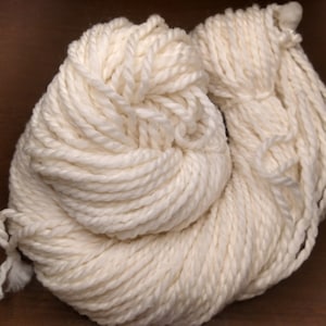 May include: A skein of white yarn, twisted and piled into a loose, round shape.