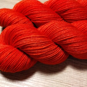 May include: A skein of bright orange yarn, wound into a ball shape. The yarn is soft and fluffy, and the color is vibrant and eye-catching.