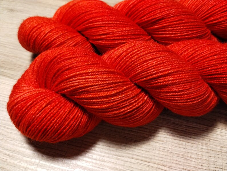 May include: A skein of bright orange yarn, wound into a ball shape. The yarn is soft and fluffy, and the color is vibrant and eye-catching.