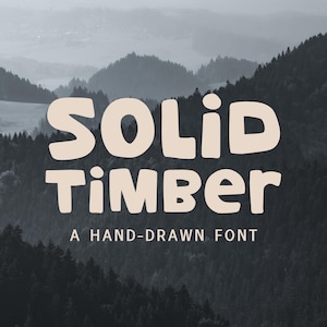 May include: The image features the words "SOLID TIMBER" in a bold, rounded font, with the tagline "A HAND-DRAWN FONT" below. The text is a light beige color, set against a backdrop of a misty mountain range.