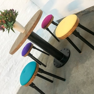 Mesa pedestal estilo industrial Button de acero teñido en polvo color castaño y negro con 4 taburetes tapizados en pura lana virgen de primera calidad