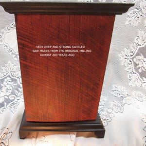 May include: A rectangular wooden box with a dark brown top and base. The box is made of reddish-brown wood with visible saw marks and the text "VERY DEEP AND STRONG SWIRLED SAW MARKS FROM ITS ORIGINAL MILLING ALMOST 200 YEARS AGO".
